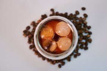 Cool black coffee in a glass, decorated around with coffee beans.