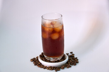 Cool black coffee in a glass, decorated around with coffee beans.