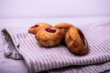 Homemade strawberry muffins on wooden tray with white checked napkin underneat.