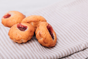Homemade strawberry muffins on wooden tray with white checked napkin underneat.