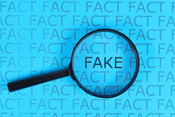 Concept for Fake News with words 'fact' in row and single word  'fake' highlighted by magnifying...