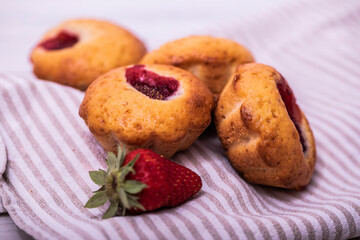 Strawberry muffin with fresh strawberries in a cut on a white wooden table.
