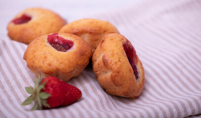 Strawberry muffin with fresh strawberries in a cut on a white wooden table.