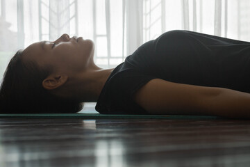 Young woman meditating at home on a yoga mat with her eyes closed