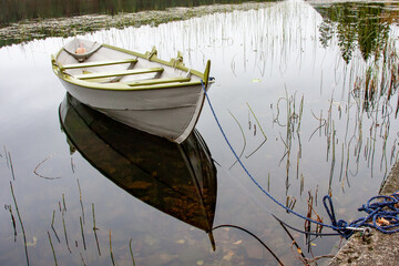 Old white row-boat on a tranquil lake