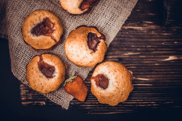 Tasty cupcake, decorated with fresh strawberry on a dark wooden background. Muffin with place for text.