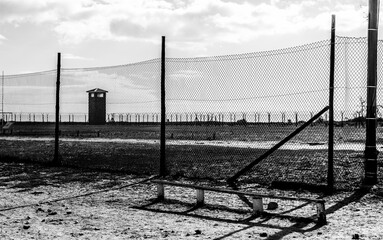 Grayscale shot of a concentration camp behind the fence