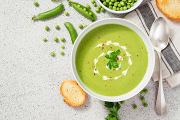Bowl of green peas cream soup on gray stone background