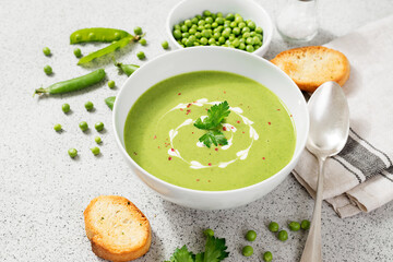 Bowl of green peas cream soup on gray stone background