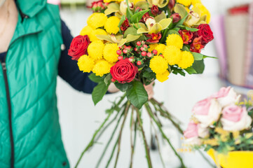 The work of the florist. Flower packaging. Creating a flower bouquet. Roses in a package. The hands of the florist. Selective focus. 