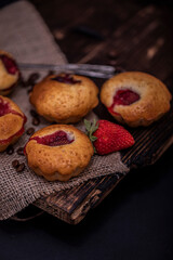 Strawberry chocolate cupcakes muffins on old wooden stand on concrete gray background.