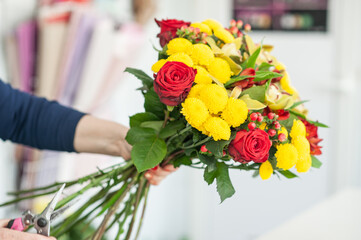 The work of the florist. Flower packaging. Creating a flower bouquet. Roses in a package. The hands of the florist. Selective focus. 