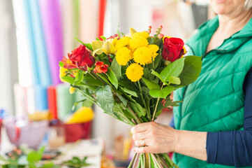 The work of the florist. Flower packaging. Creating a flower bouquet. Roses in a package. The hands of the florist. Selective focus. 