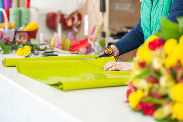 The work of the florist. Flower packaging. Creating a flower bouquet. Roses in a package. The hands of the florist. Selective focus. 