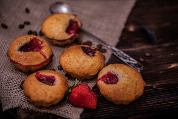 Strawberry muffin and coffee beans on a wooden board on a dark wood background. Chocolate muffins on dark background, selective focus.