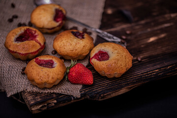 Strawberry muffin and coffee beans on a wooden board on a dark wood background. Chocolate muffins on dark background, selective focus.