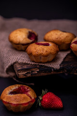 Strawberry muffin and coffee beans on a wooden board on a dark wood background. Chocolate muffins on dark background, selective focus.