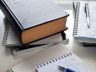 On the table are old books, notebooks with notes, pens. Study, abstract, education, scientific work.