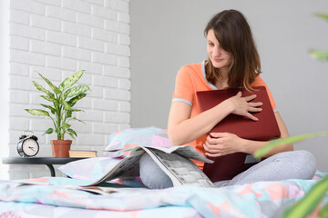 Girl sitting on the bed and reading a newspaper with job advertisements