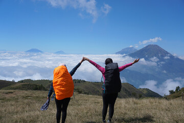 Young couple hiking in the mountains, enjoying view from top of the Mt. Prau. Dieng, Wonosobo province, Central Java, Indonesia