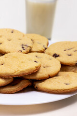 Delicious chocolate chip cookies plate with a glass of milk on the background.  on a white Isolated background