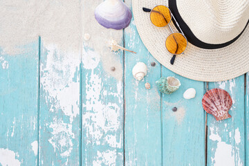 pattern sea shells colorful and hat, sunglasses on a blue wooden old background with sand. Summer time vacation concept. 