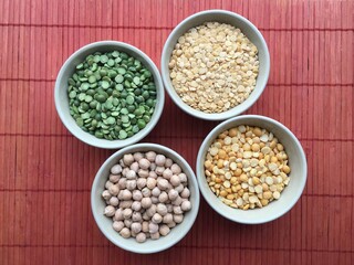 Round bowls with legumes, peas, chickpeas and lentils on a red background. A bowl of food on a plate. High quality photo