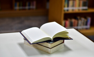 Open Book on wood table and blurred bookshelf in the library, education background, back to school concept.