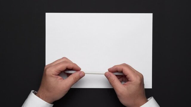 top view of a blank sheet of paper and a businessman's hands on a black table, white shirt