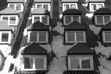 Grayscale shot of a snow-covered building roof with windows - Powered by Adobe