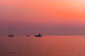 silhouette of fishing boats on lake at sunset