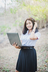 Asian young girl in school uniform are using laptop for education and communication at countryside of Thailand.