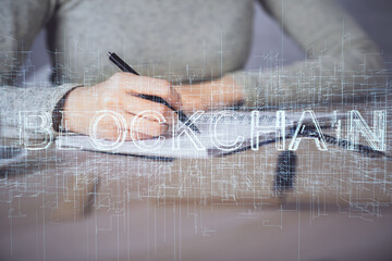 Cryptocurrency hologram over woman's hands writing background. Concept of blockchain. Multi exposure
