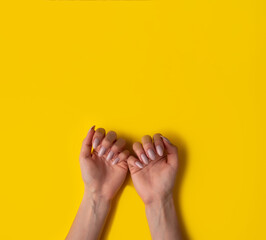 Female hands with a beautiful manicure on a yellow background,top view