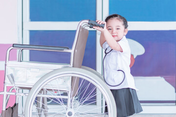 A Cute and lovely Asian baby girl in nurse uniform dress holding wheelchair