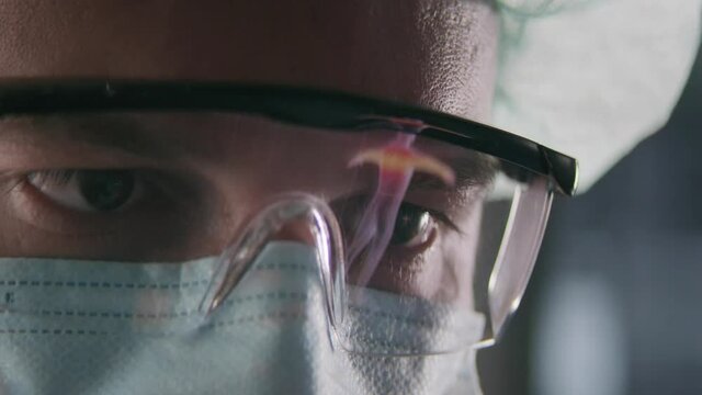 A scientist researching a human body scan in a modern laboratory. We see a xray reflection in his protective glasses...Shot on RED HELIUM.