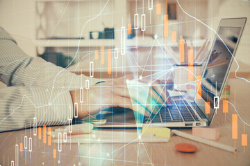 Double exposure of stock market graph with man working on laptop on background. Concept of financial analysis.