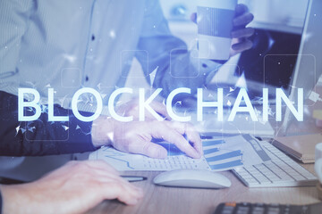 Crypto currency theme hologram with businessman working on computer on background. Concept of blockchain. Multi exposure.