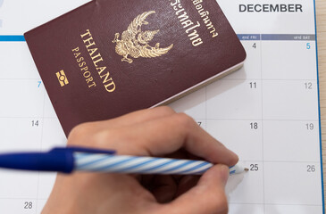 Hand writes on calendar with Thai passport. 