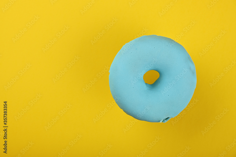 Wall mural One blue glazed donut over yellow