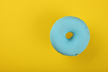 One blue glazed donut over yellow