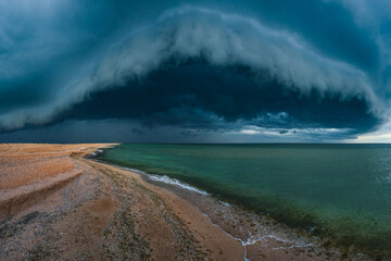 Panorama of dramatic picturesque seascape with 
heavy dark thunderclouds. Sea ​​coast before the storm, shelf cloud. Copy space on the dark water. 