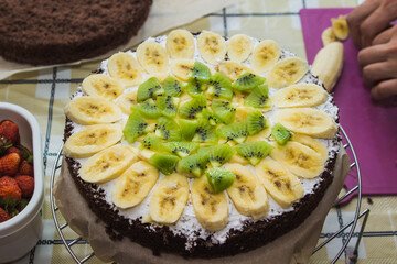 Making homemade creamy fruit cake. Kiwi cake and banana are decorated. Cake ingredients.