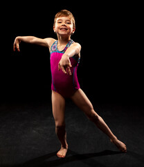 Obraz premium Young gymnast posing on a black background. 