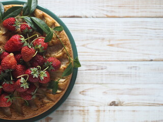 Soft or blurry focus. Apple pie or biscuit with strawberries on top. White wooden background.Top view.