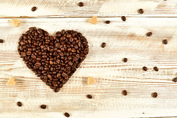 I love coffee concept. Coffee beans shaped as heart and spread brown sugars on wooden plank . Blank copy space.