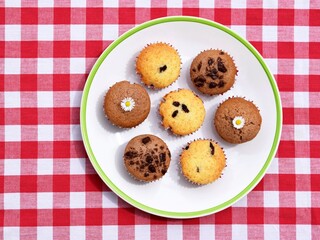 Delicious homemade vanilla muffins with raisins and cocoa muffins, some decorated with edible daisy flowers