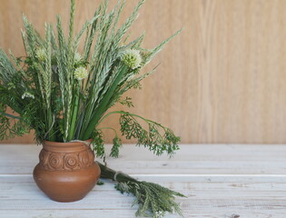 Bouquet of ears of grass and onion flowers on a wooden background.Village background.