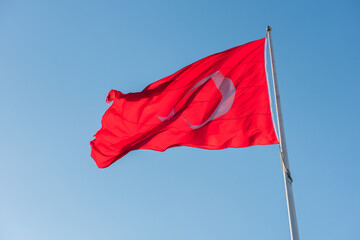 Turkish flag waving on blue sky background.