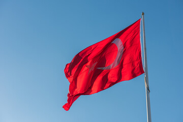 Turkish flag waving on blue sky background.